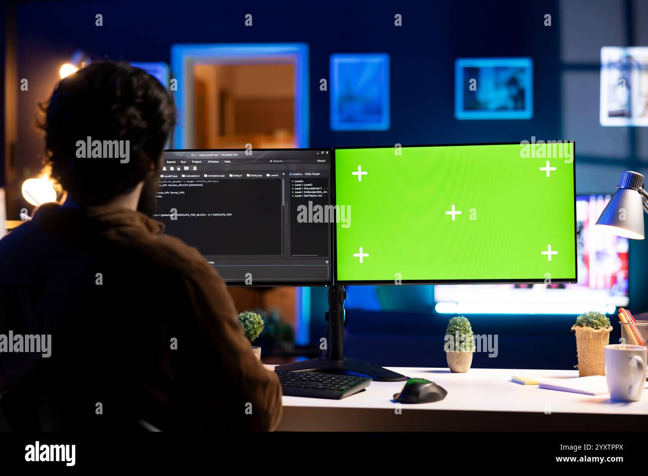 Programmer doing software debugging on green screen PC at home, checking broken lines of code displayed on monitors. IT professional in living room fixing coding problems on mockup computer Stock Photo