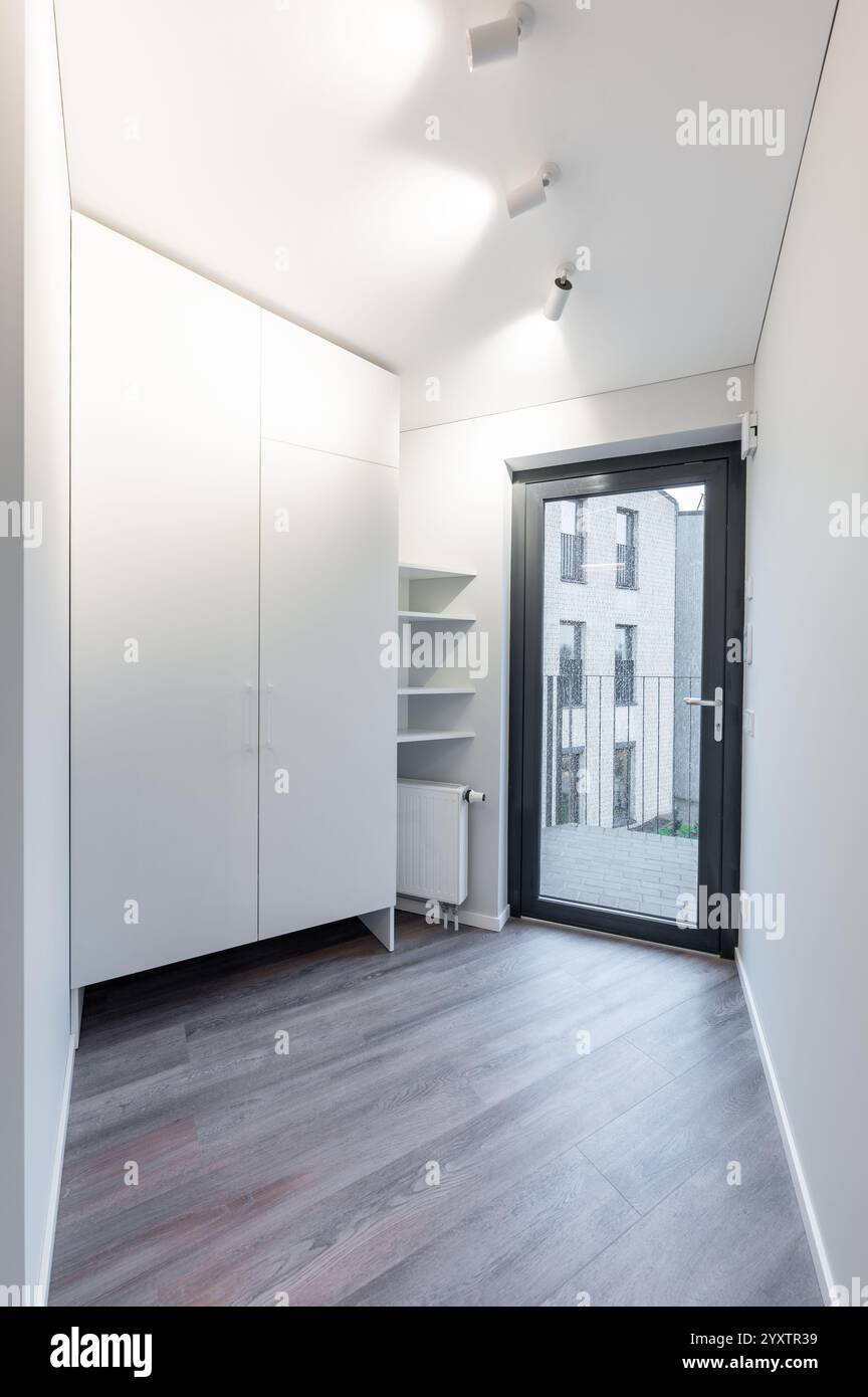 Bright and clean interior hallway with natural wood flooring, a ...