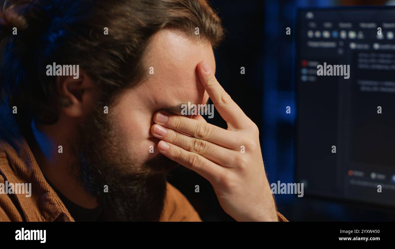 Disappointed computer scientist puzzled after being unable to remove all bugs while coding on workstation desktop. Teleworking IT specialist confused by troubling script errors, camera A close up Stock Photo