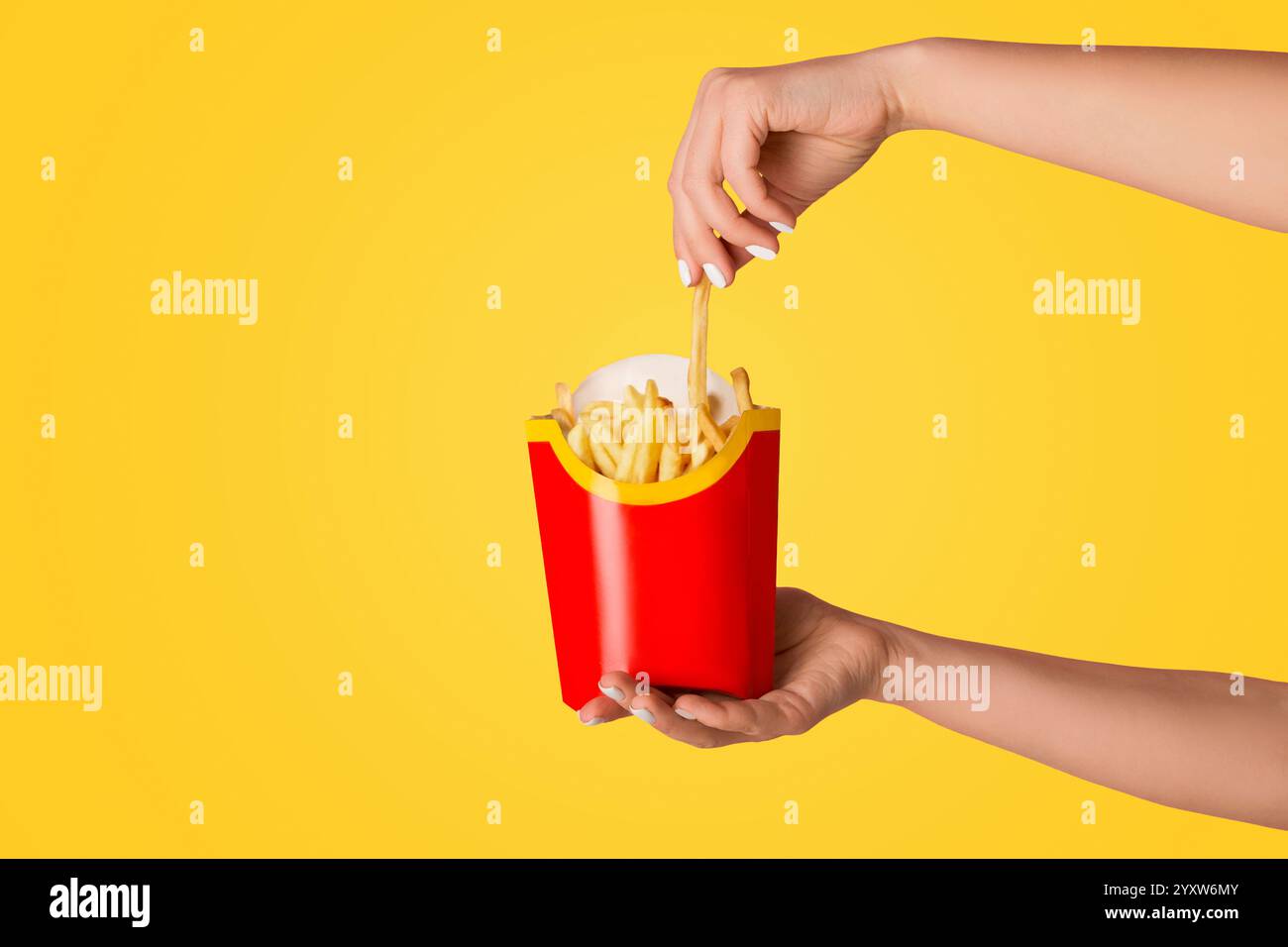 KHARKIV, UKRAINE - APRIL 4, 2020: Young girl holding pack of french fries from McDonald's on pink background Stock Photo