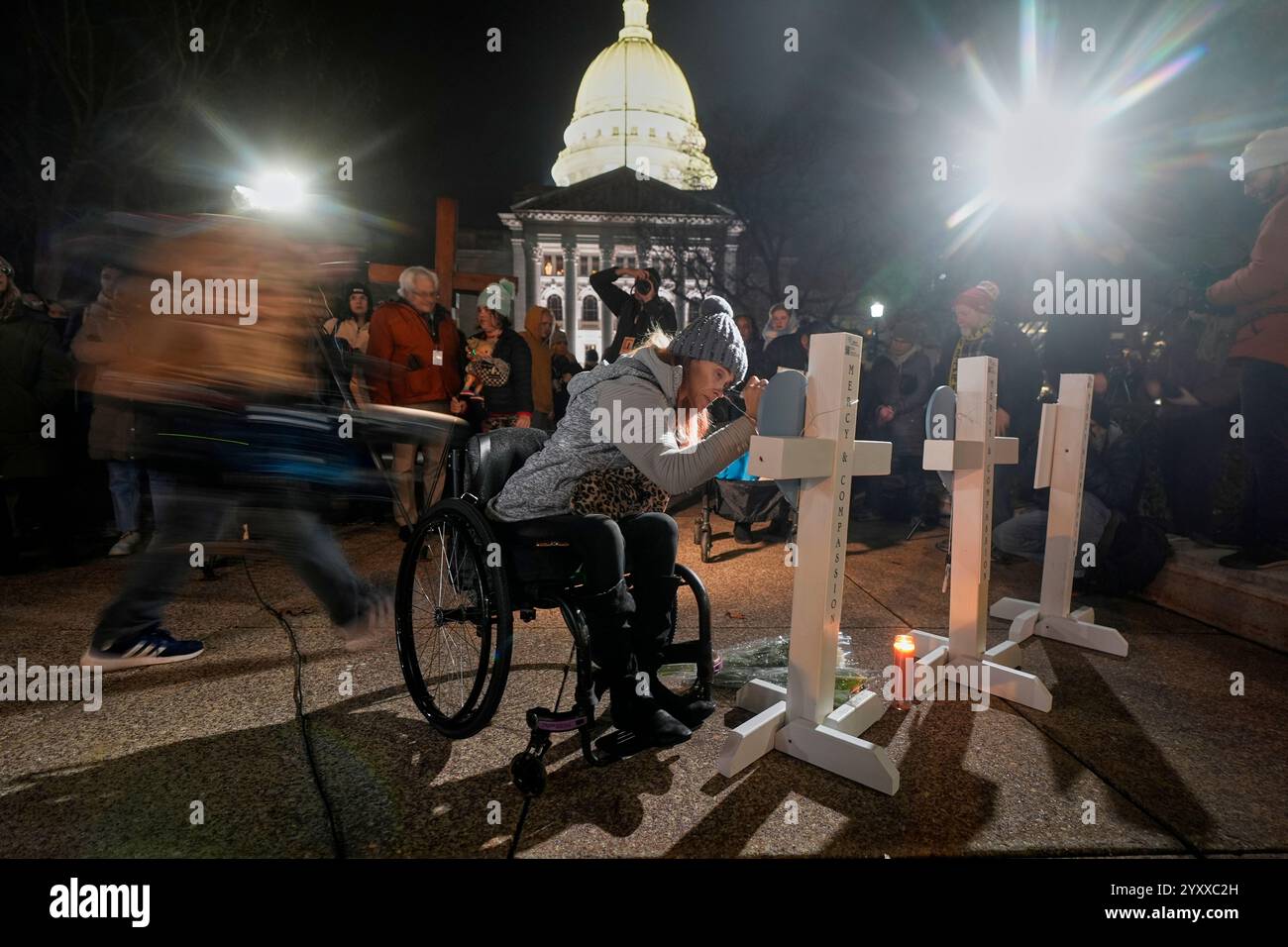 A supporter signs a cross during a candlelight vigil Tuesday, Dec. 17, 2024, outside the Wisconsin Capitol in Madison, Wis., following a shooting at the Abundant Life Christian School on Monday, Dec. 16. (AP Photo/Morry Gash) Stock Photo