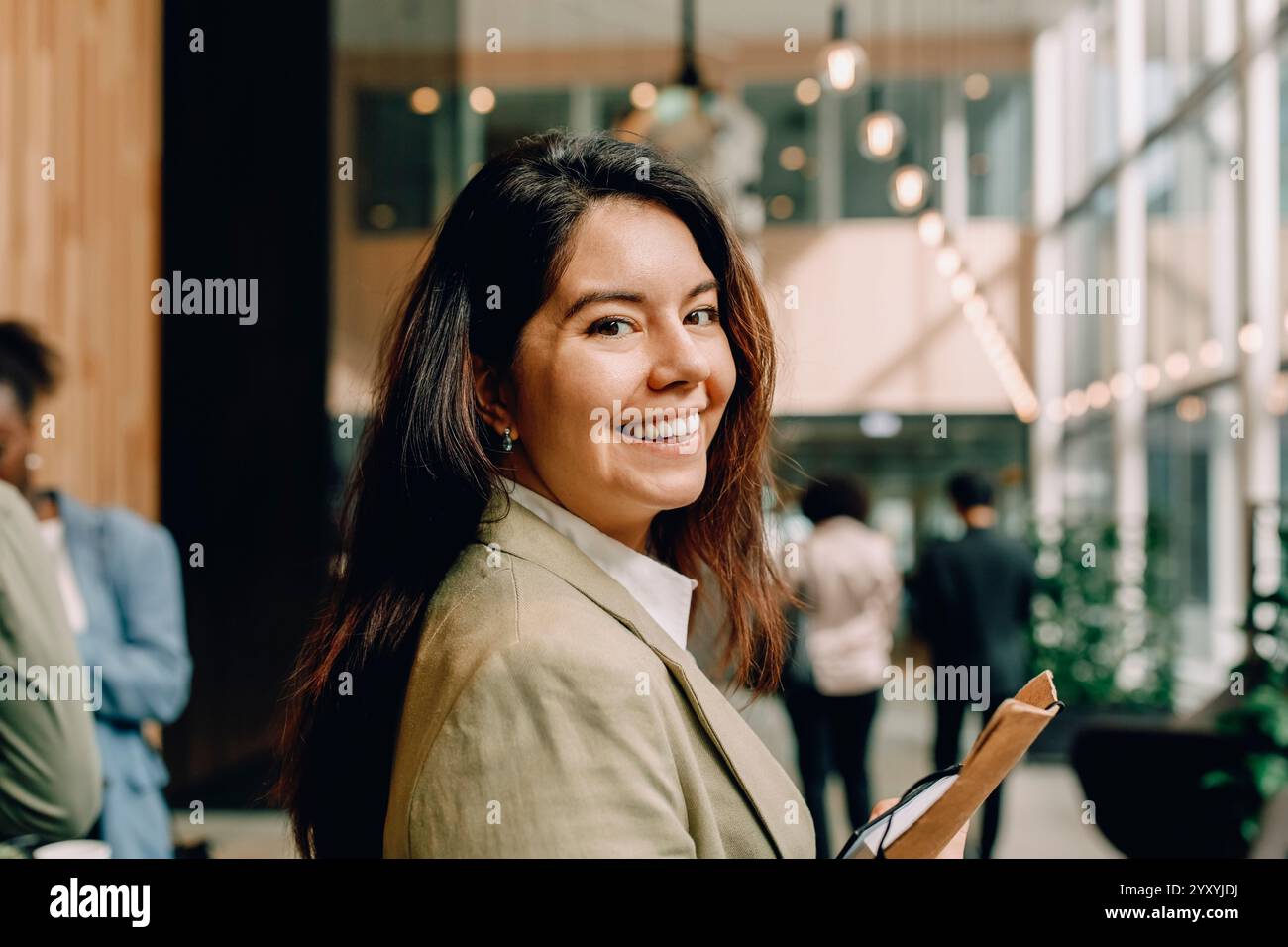 Side view portrait of smiling businesswoman with long hair at convention center Stock Photo
