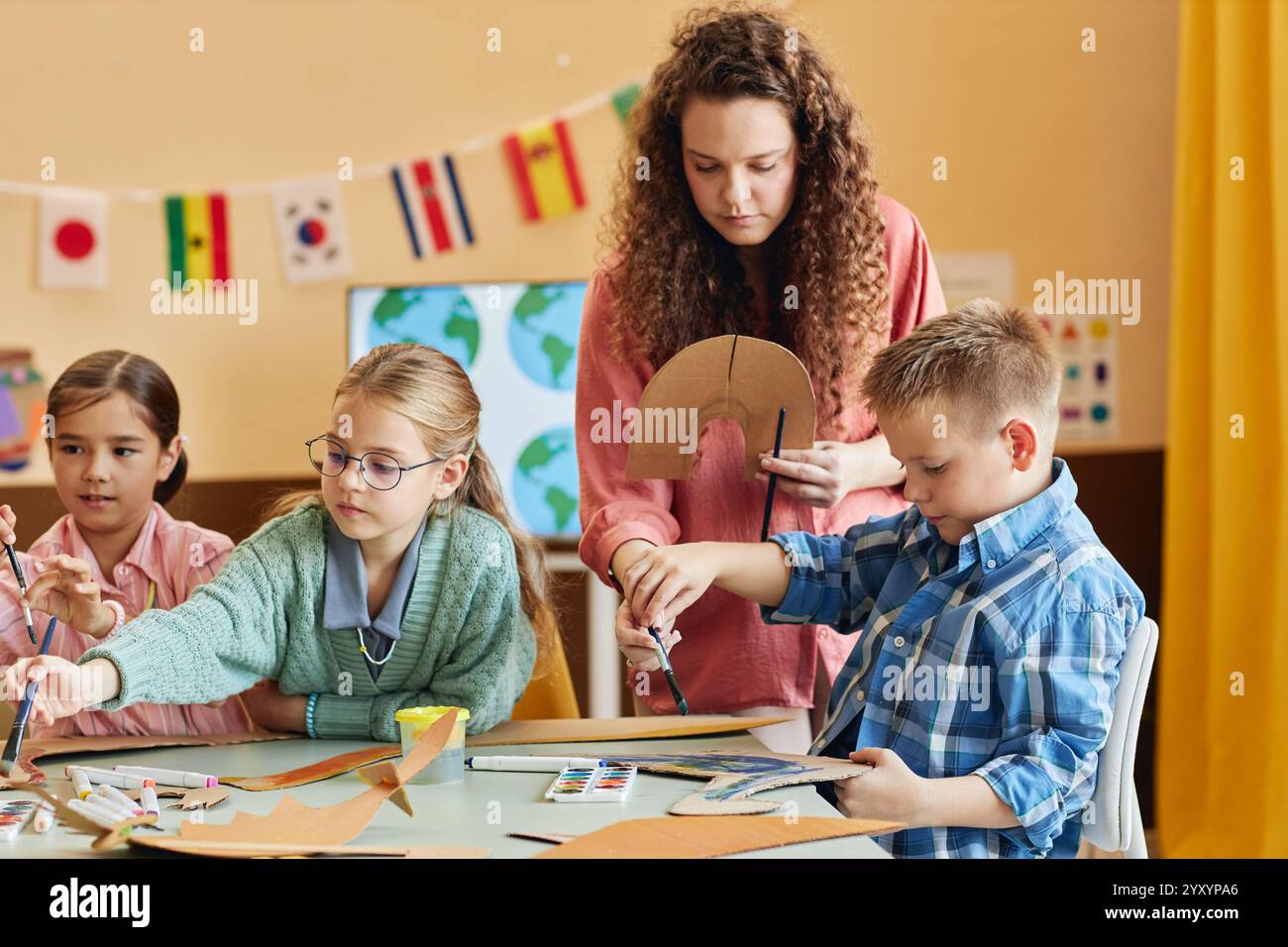 Colorful portrait of kind young teacher assisting children during art ...