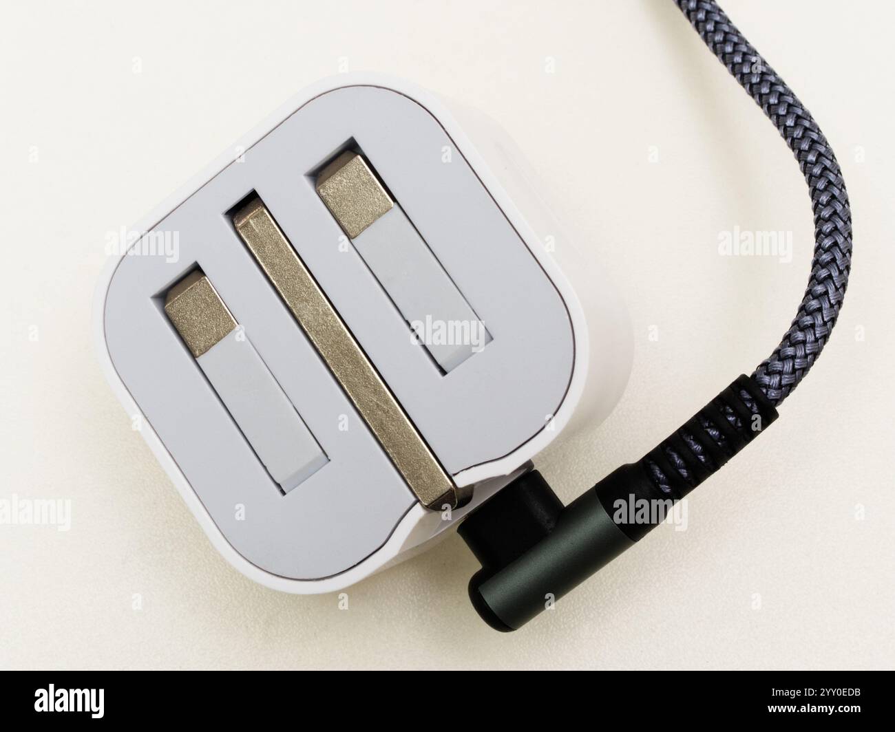 Closeup isolated shot of a UK British electric travel plug and cable or cord, with 3 folded pins which lift up to connect to a mains socket. Stock Photo