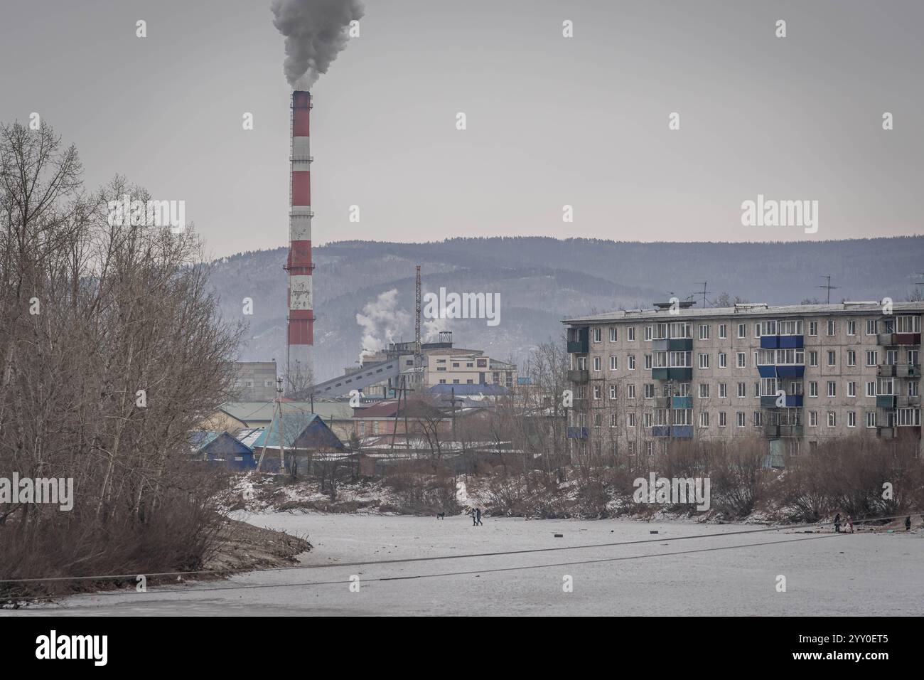 The factory smoking chimney by the frozen river in Chita, Russia, Zabaykalsky Krai. Stock Photo