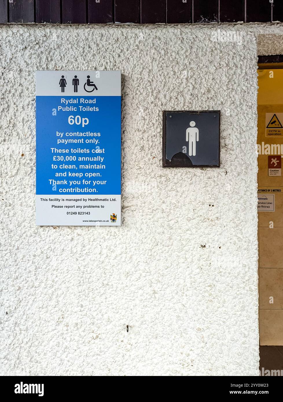 Contactless payment to use sign on the wall outside Rydal road men's public toilets, featuring blue background and white  text. - Smartphone Captured Stock Image