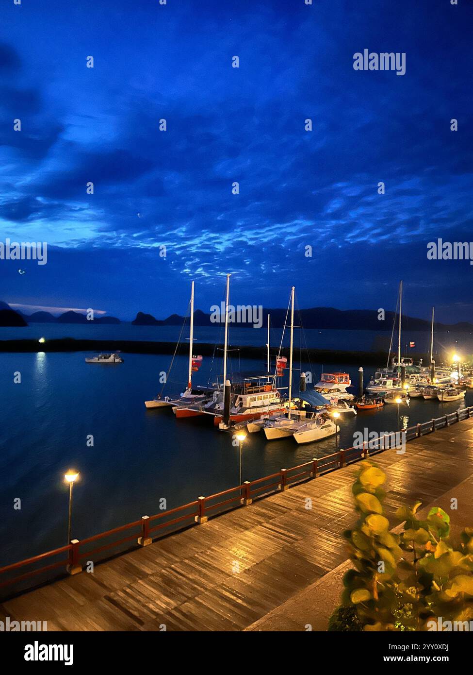 Serene sunrise over a marina with yachts, viewed from a cozy balcony illuminated by warm lighting – perfect for travel, lifestyle, and luxury concepts - Smartphone Captured Stock Image