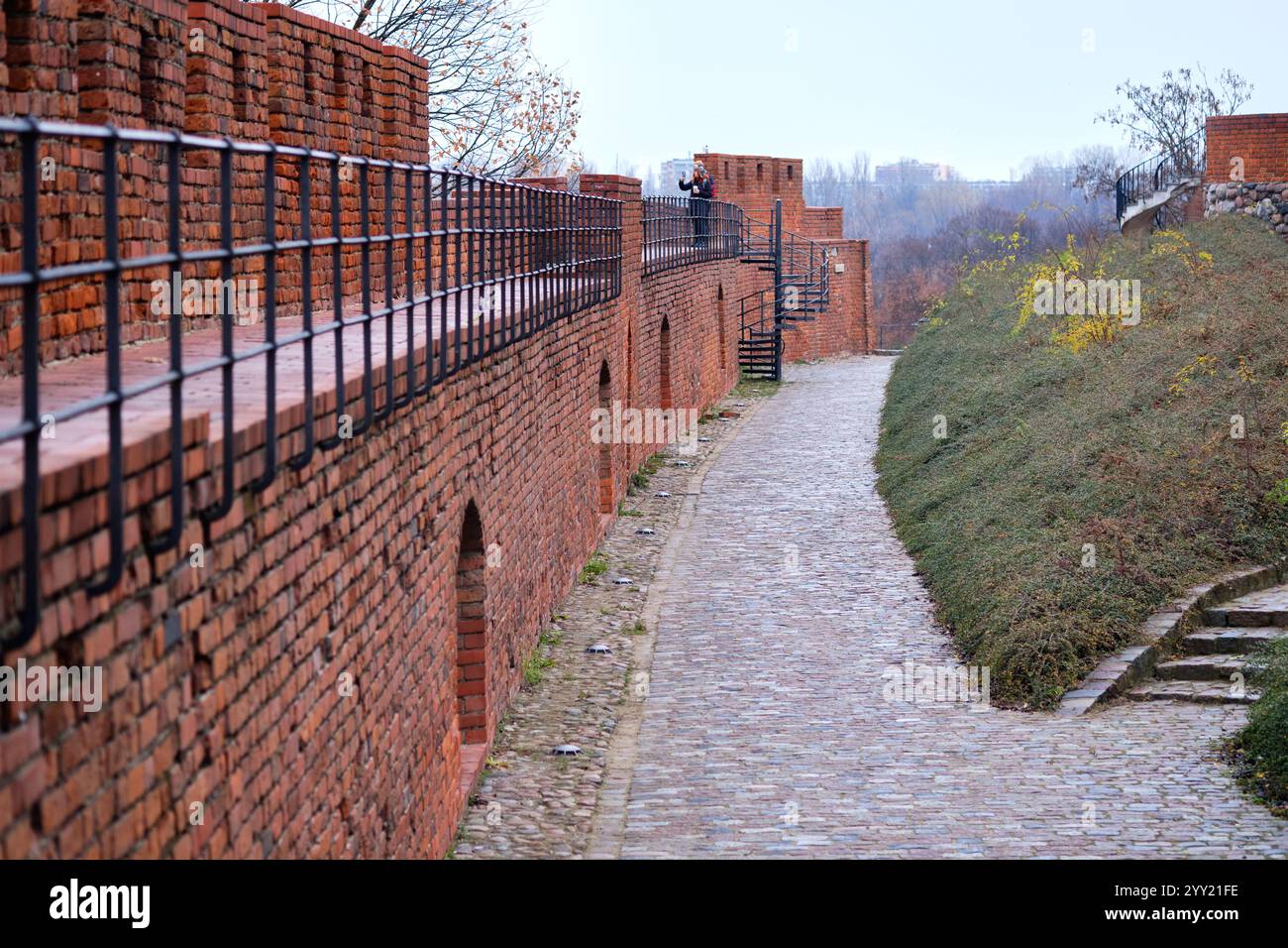 Rustic Fortress A person strolls along a historic brick fortress wall, observing the ...