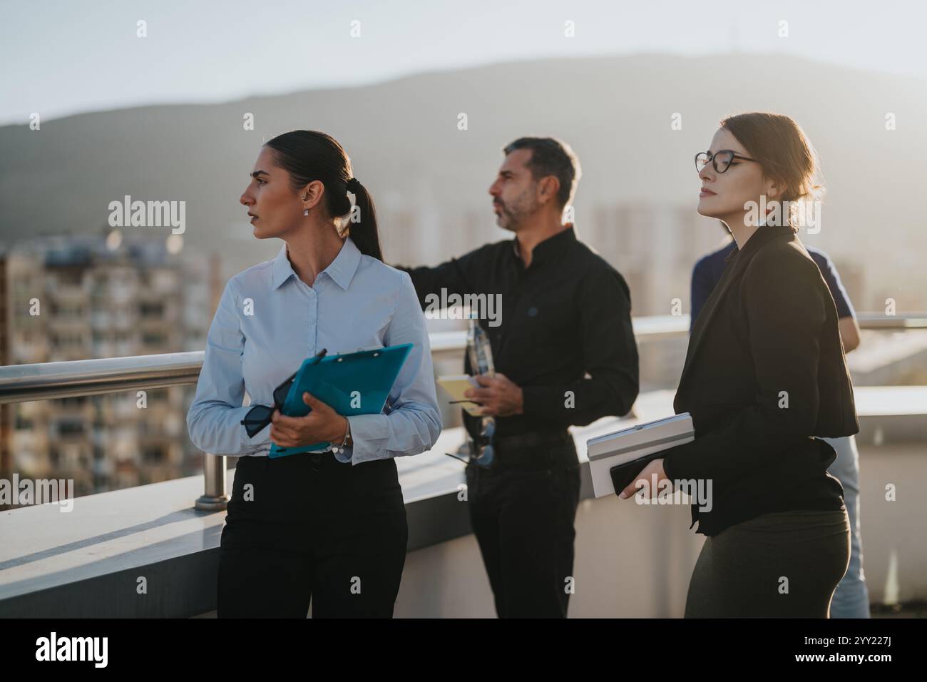 Multicultural business team brainstorming on rooftop at sunset Stock Photo