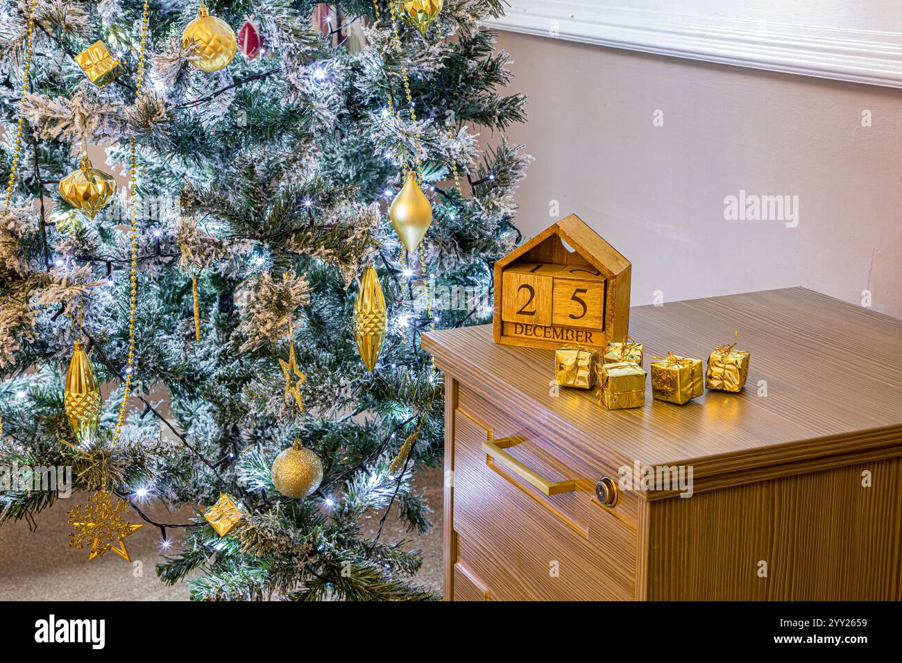 Christmas tree with gold decorations and twinkling lights next to a ...