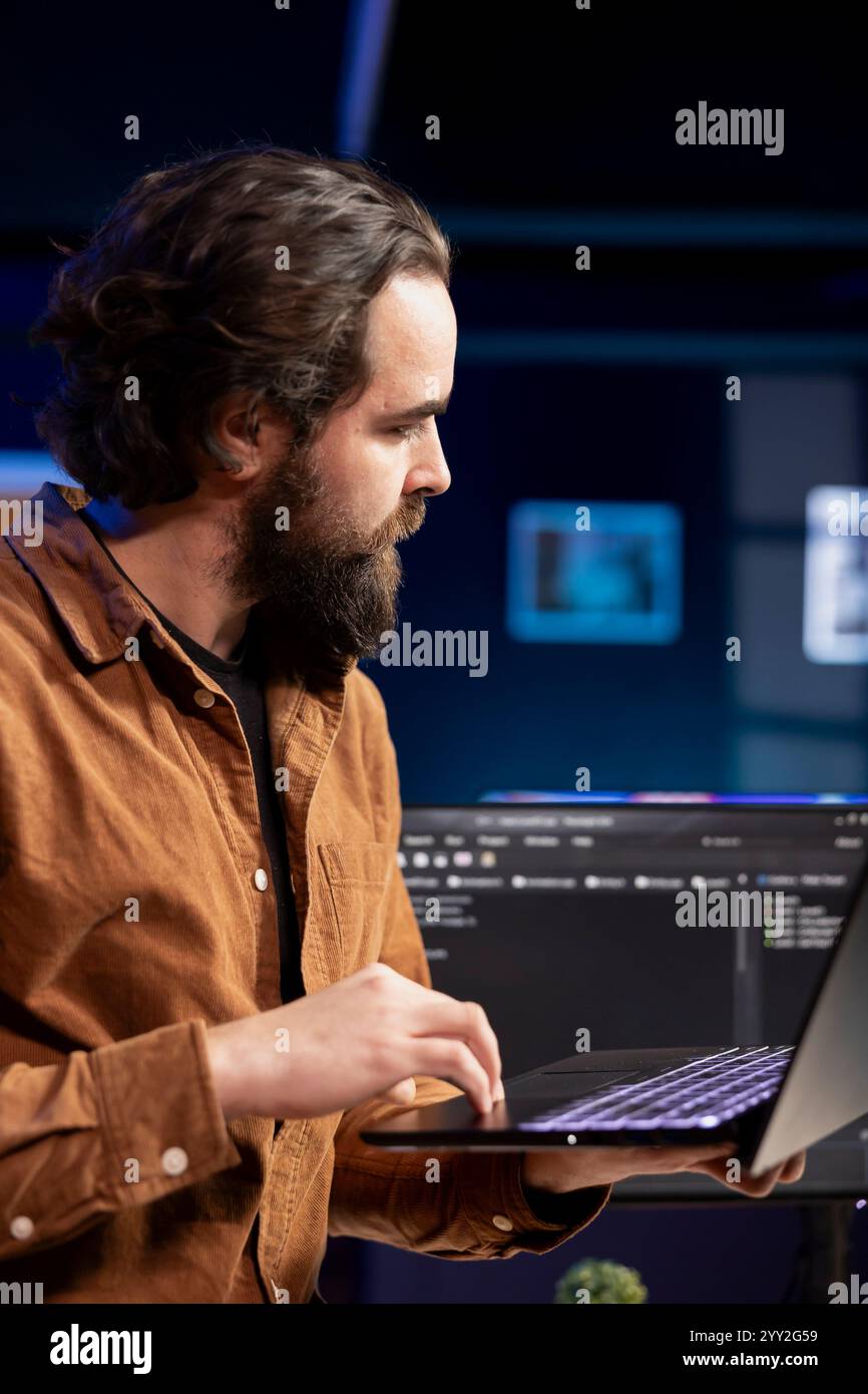 Computer engineer crosschecking between laptop and monitor, implementing security measures to protect company systems. IT worker comparing software code between notebook and PC Stock Photo
