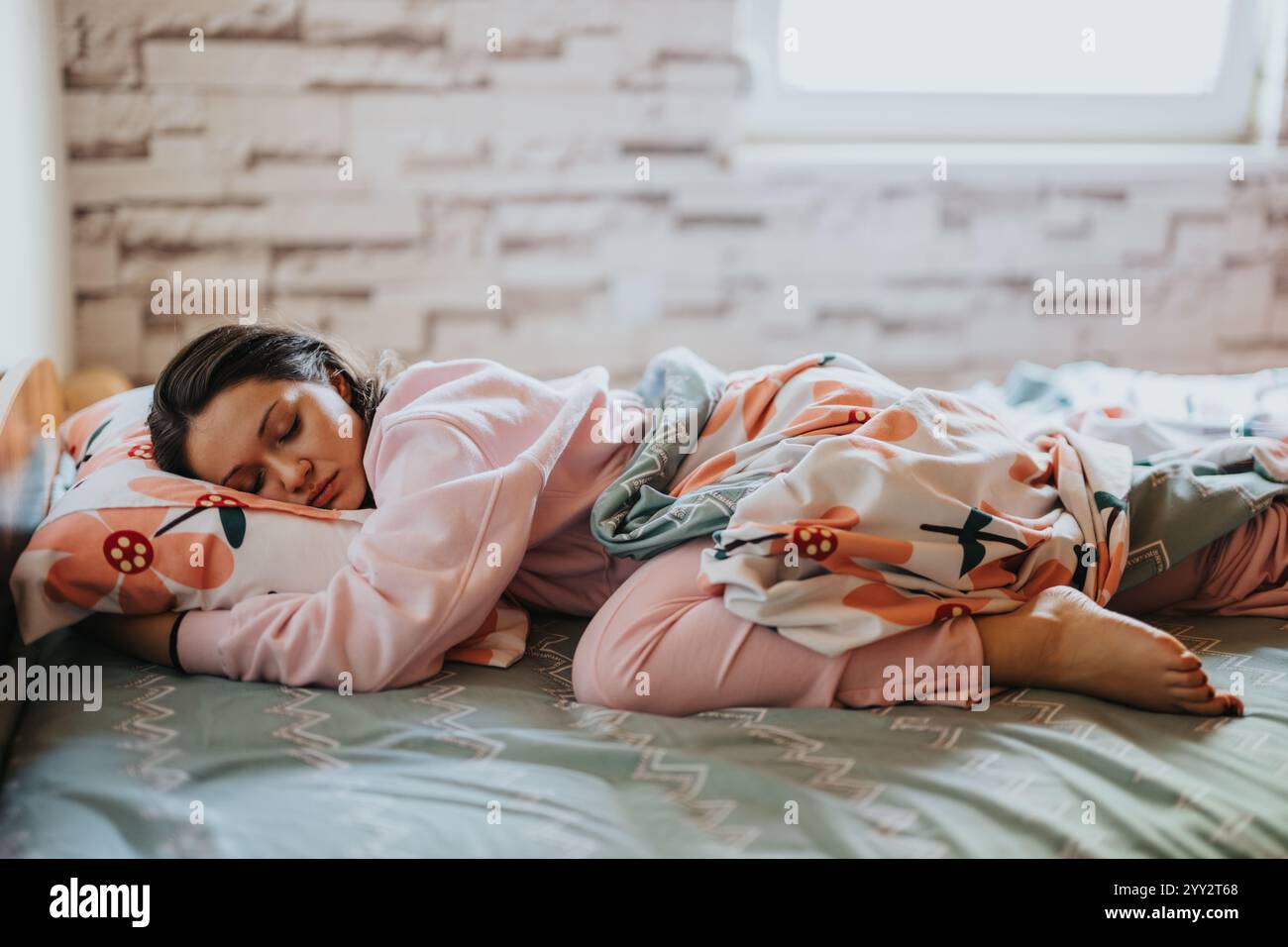 Young woman in pajamas sleeping peacefully in cozy bedroom Stock Photo