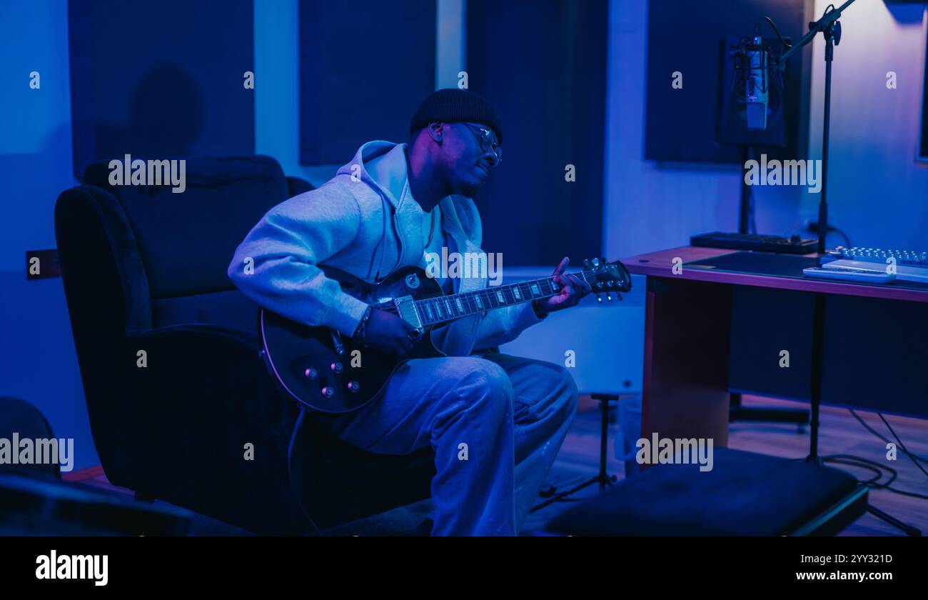 A solo musician plays an electric guitar in a stylish recording studio ...