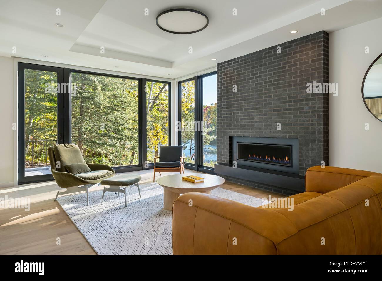Modern living room with large windows and view of trees and lake Stock ...