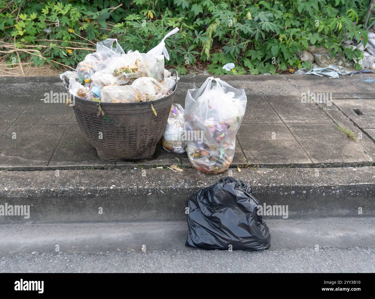 Front view of garbage in black plastic bag at garbage dump on roadside or footpath is in downtown area. Stock Photo