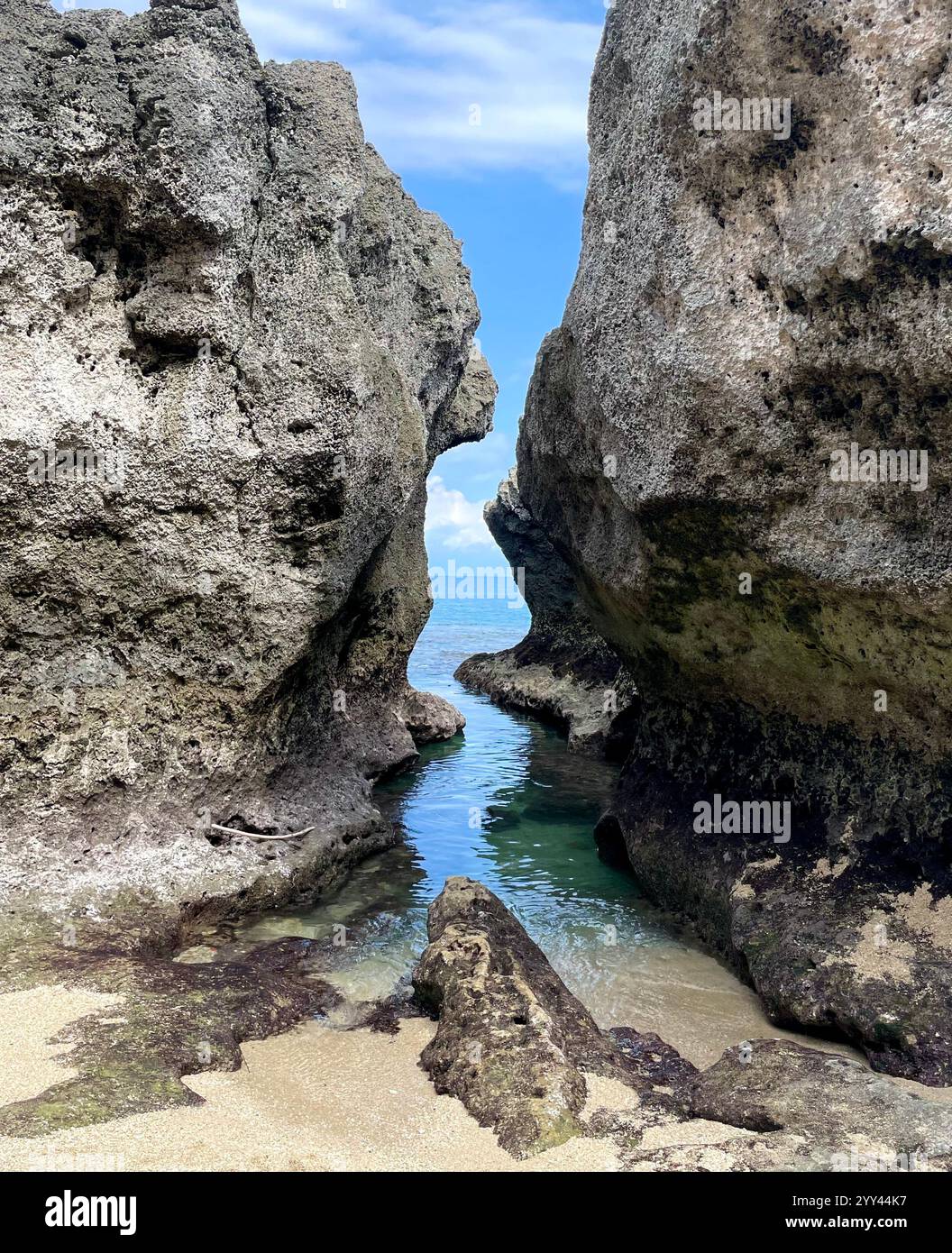 Rock structures separated by ocean water and a sandy beach - Smartphone Captured Stock Image