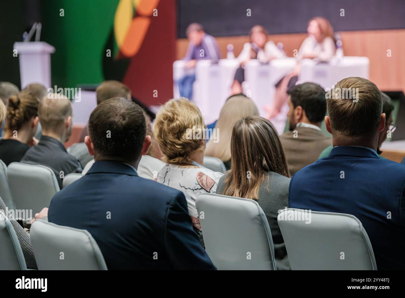 Conference room with audience listening to panel discussion on stage ...