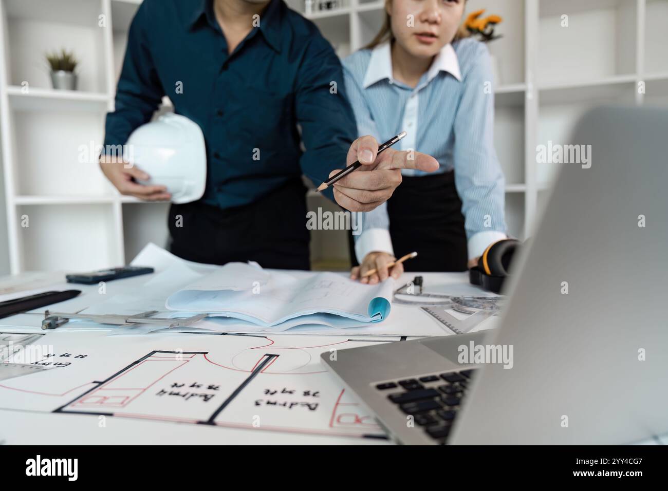 Engineers Collaborating on Architectural Design Plans in Modern Office Environment Stock Photo