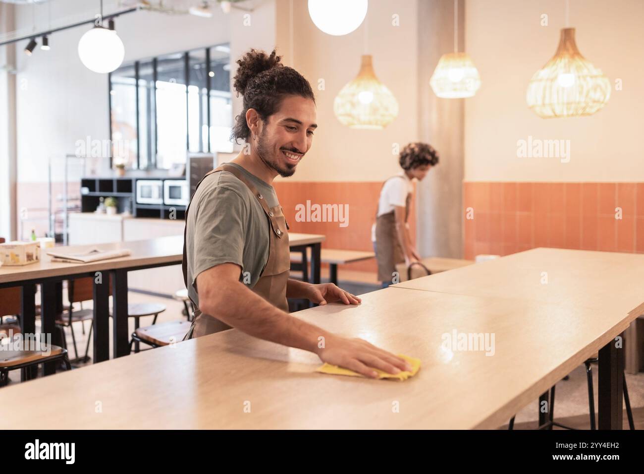 Two cafe workers clean tables in a contemporary coffee shop The bright ...