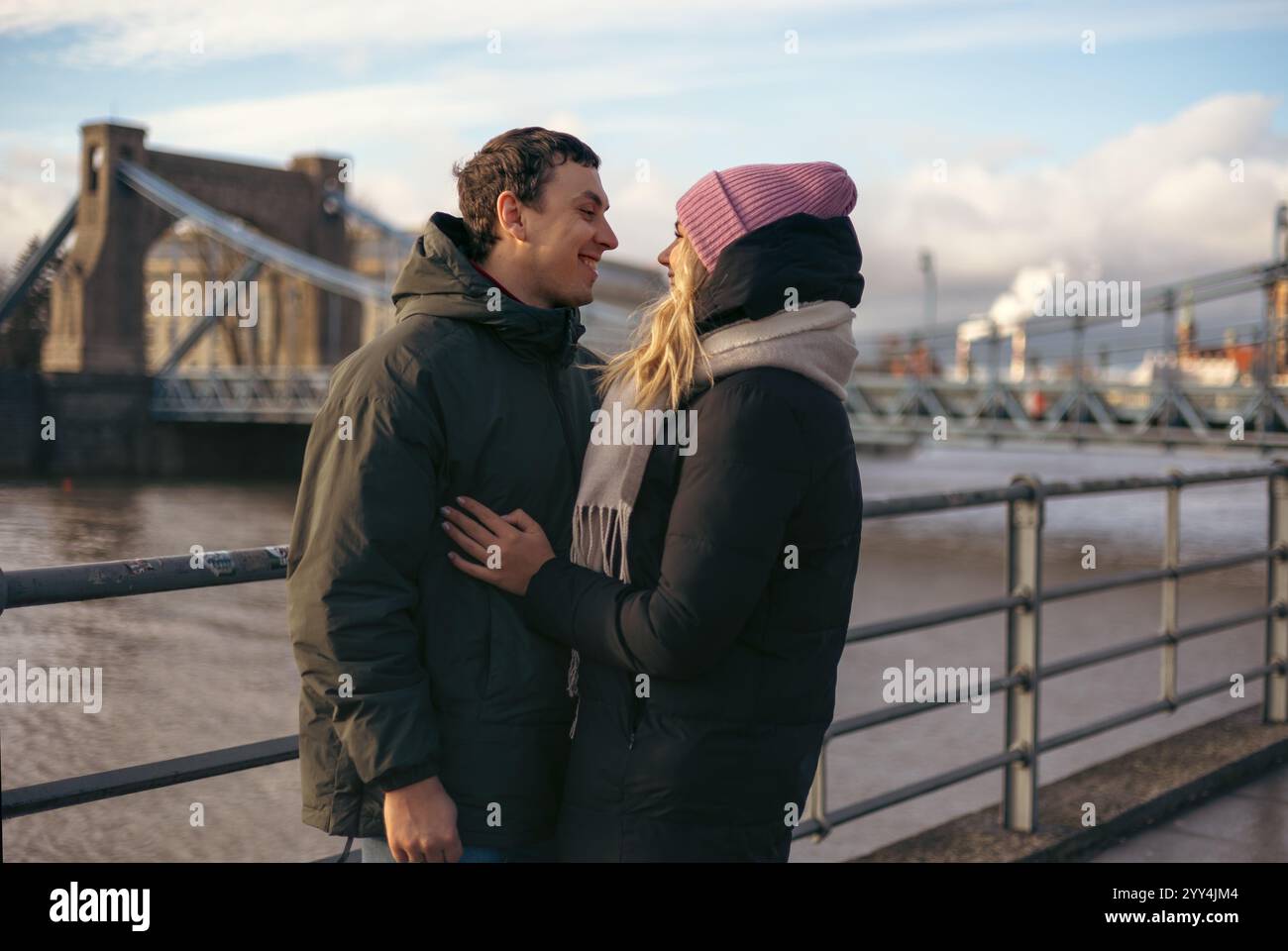 A young married couple, enjoys a leisurely stroll in the city of Wroclaw, Poland looking at each other. Both dressed warmly for the cold, they share a Stock Photo