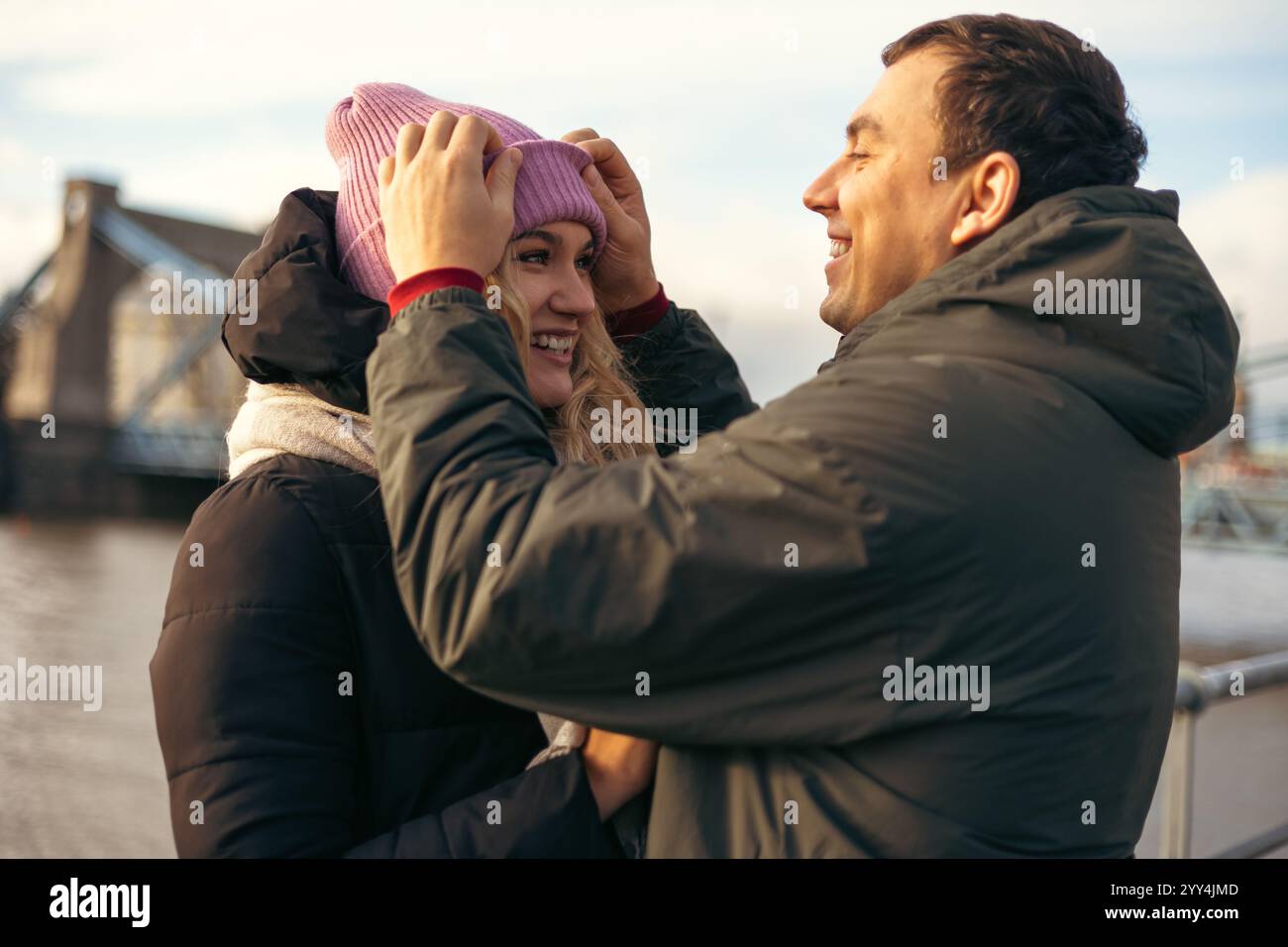 A young married man and woman share a joyful moment walking together in Wroclaw, Poland during the cool season. They are looking at each other, smilin Stock Photo
