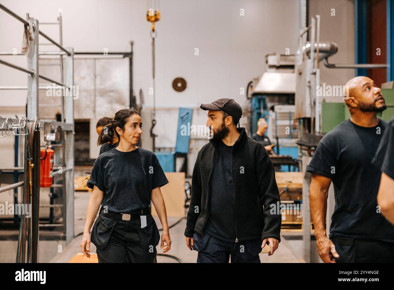 Male and female warehouse worker talking with each other while standing in distribution factory Stock Photo