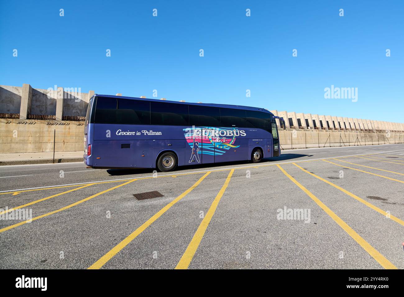 Civitavecchia, Italy - December 19, 2024: A blue tour bus marked Crociere in Pullman and EUROBUS is parked in a lot with yellow lines, showcasing tran Stock Photo