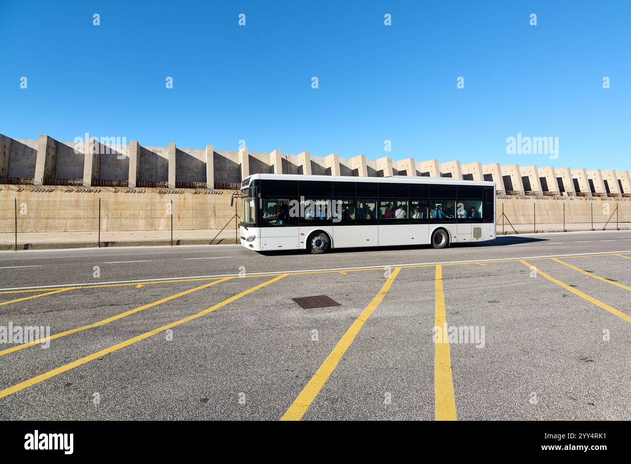 Civitavecchia, Italy - December 19, 2024: An urban bus drives down an empty road, highlighting efficient public transportation and urban infrastructur Stock Photo