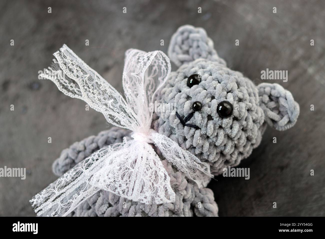 Handmade crochet teddy bear with a bow on a gray background Stock Photo ...