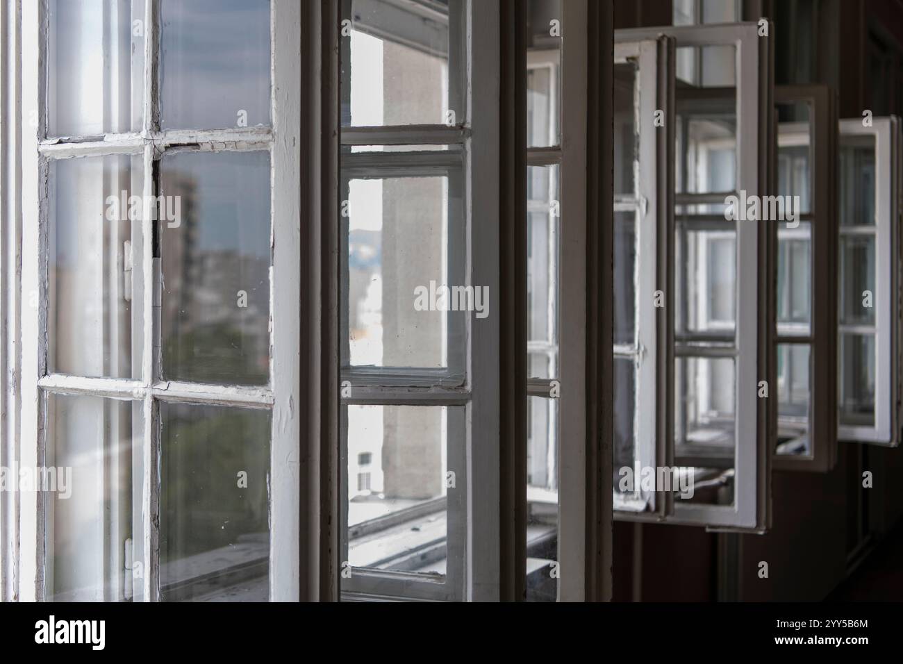 Row of old vintage white open windows in school classroom. Natural lighting trough the window. Closeup window frame. Stock Photo