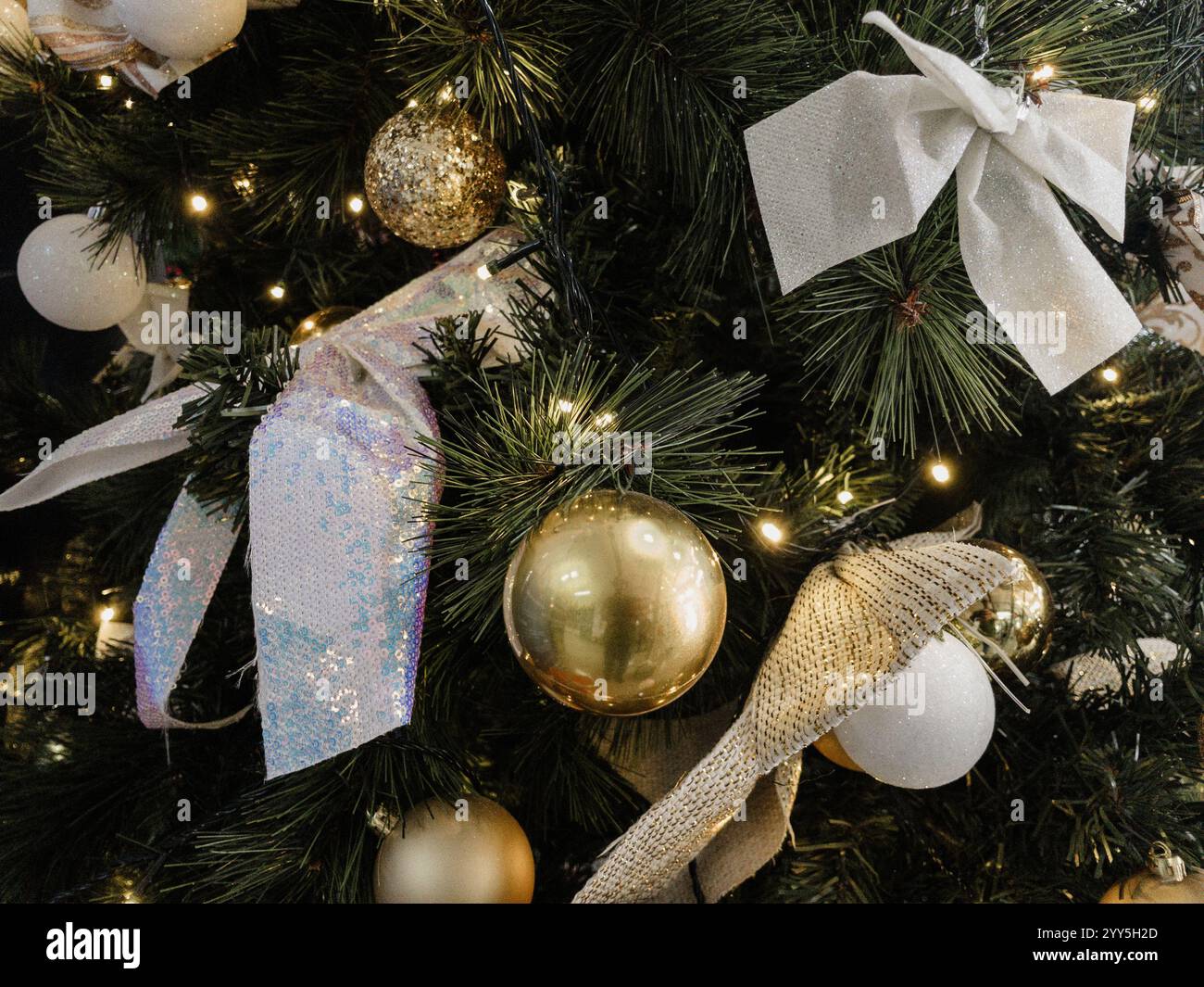 A view of golden balls, white bows and lights on the Christmas tree - Smartphone Captured Stock Image