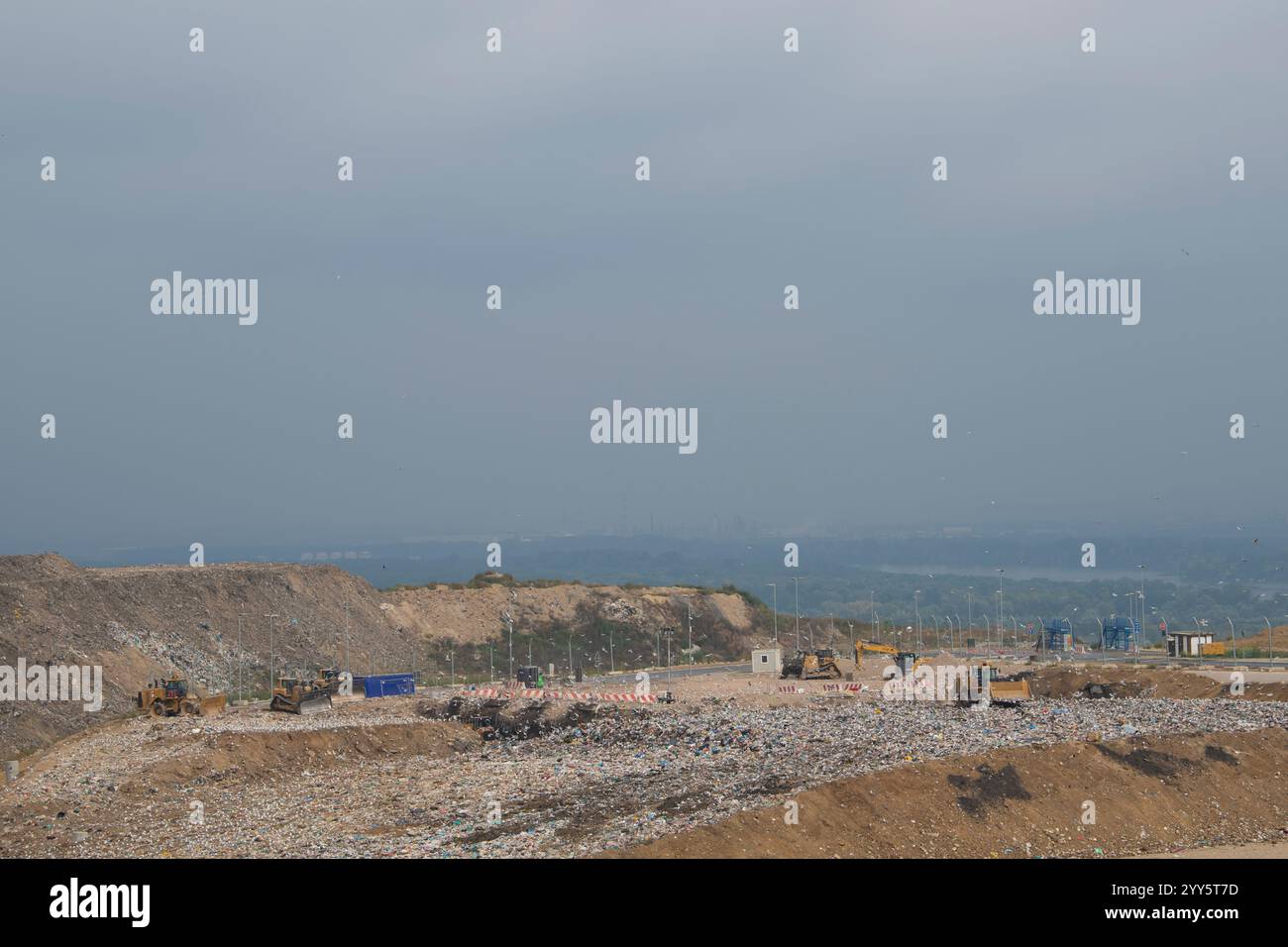 Dump trucks unloading garbage over vast landfill. Environmental