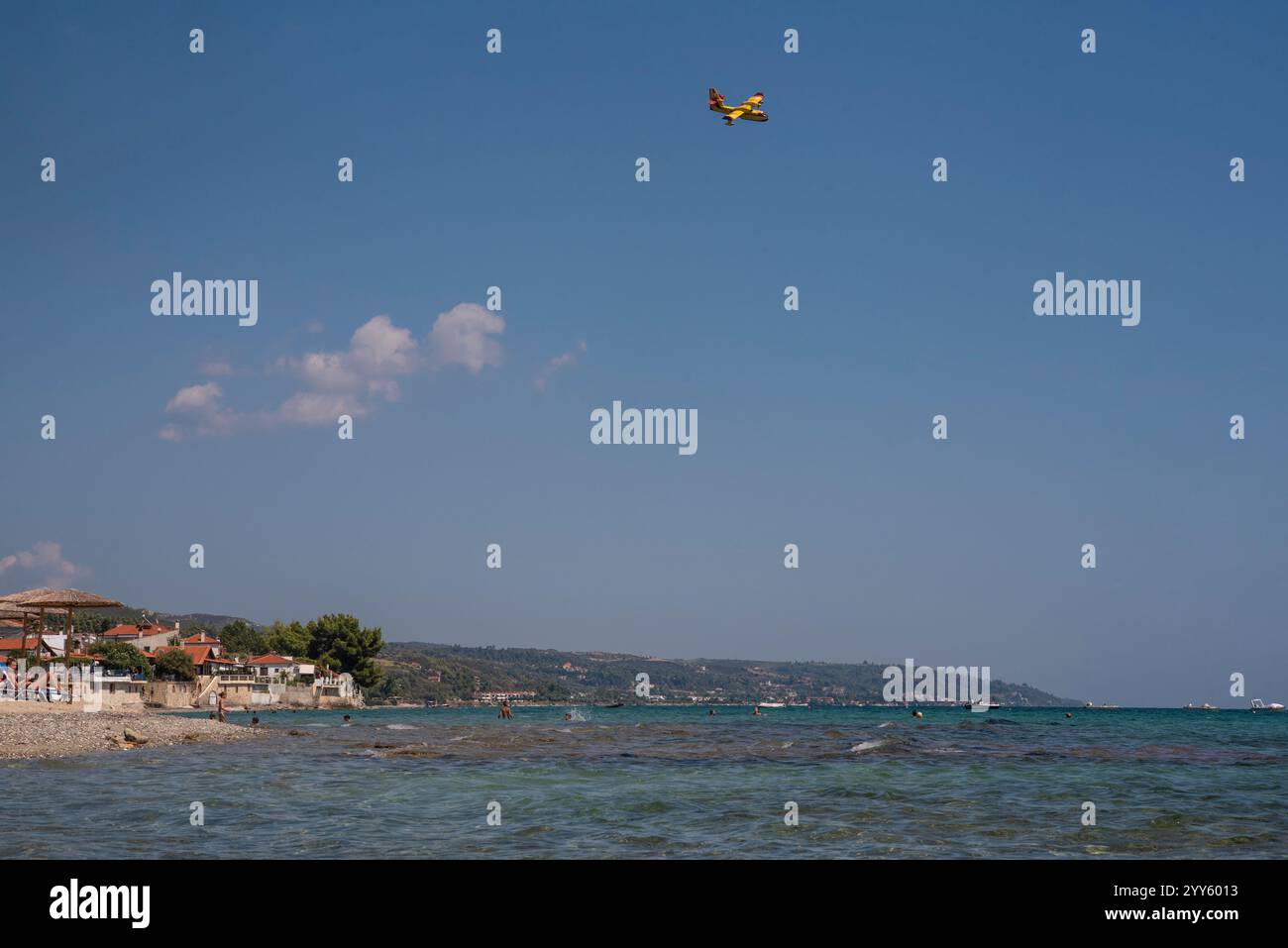 Canadair, Fire-Fighter Airplane, a twin-engined water bomber preparing to take water from sea near beach full of people and dump it on a forest fire. Stock Photo