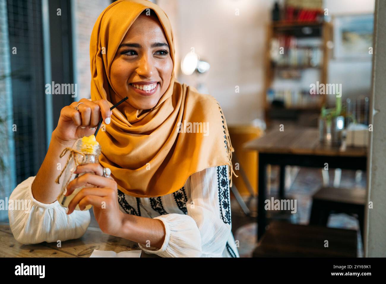 Smiling muslim woman drinking juice in cafe and wearing hijab Stock ...