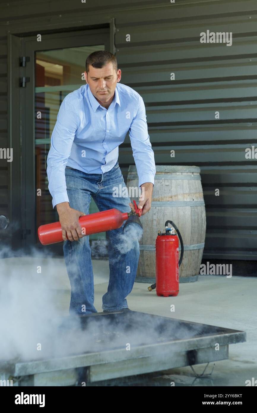 male professional checking a fire extinguisher Stock Photo