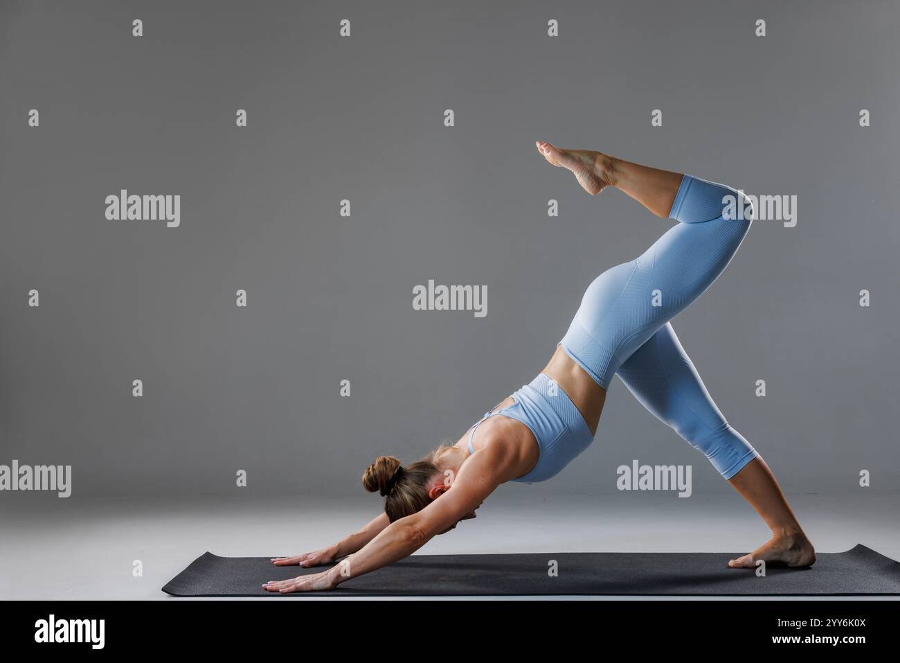 Young woman in blue sportswear practicing yoga extended asana in studio ...