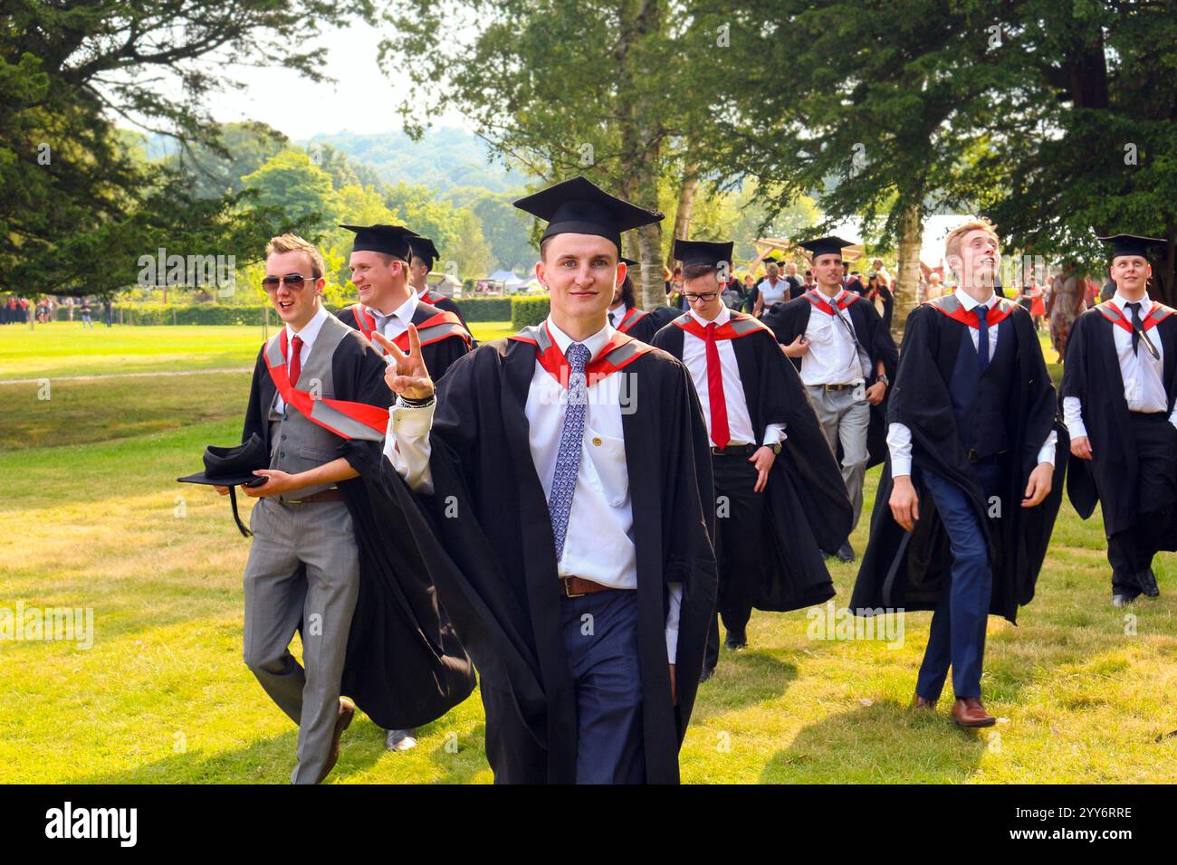 group of students walking and laughing after degree graduation ceremony ...