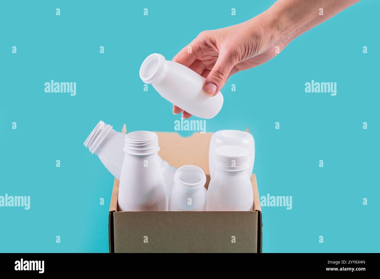 Womans hand drops white plastic bottle into container Stock Photo