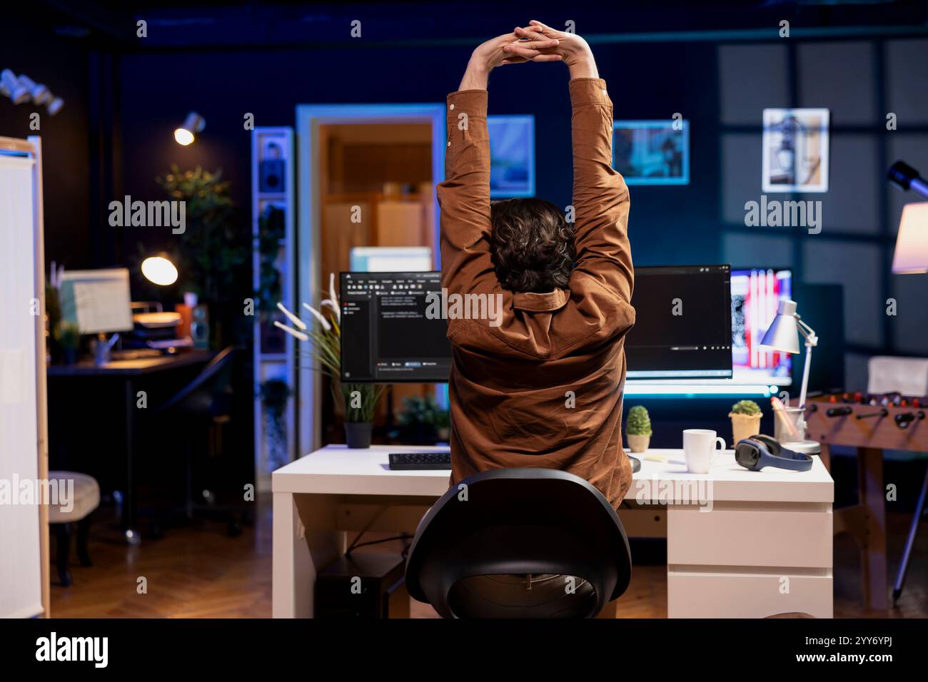 Developer doing software quality assurance, stretching after reading source code, feeling tired. IT admin relaxing muscles after inspecting coding to fix potential issues all day Stock Photo