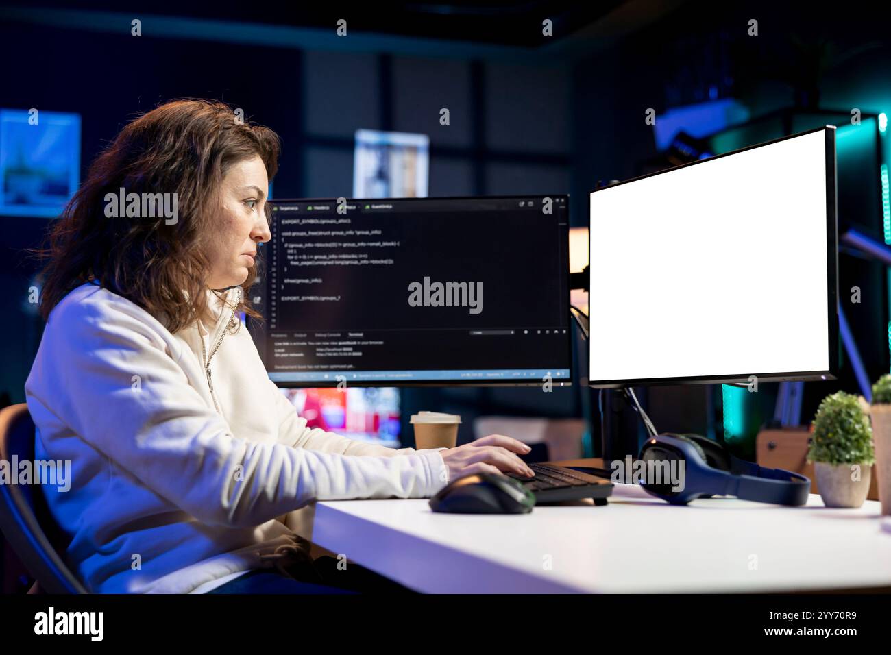 Programmer doing software debugging on isolated screen PC at home, checking broken lines of code displayed on monitors. Woman in living room fixing coding problems on mockup computer Stock Photo