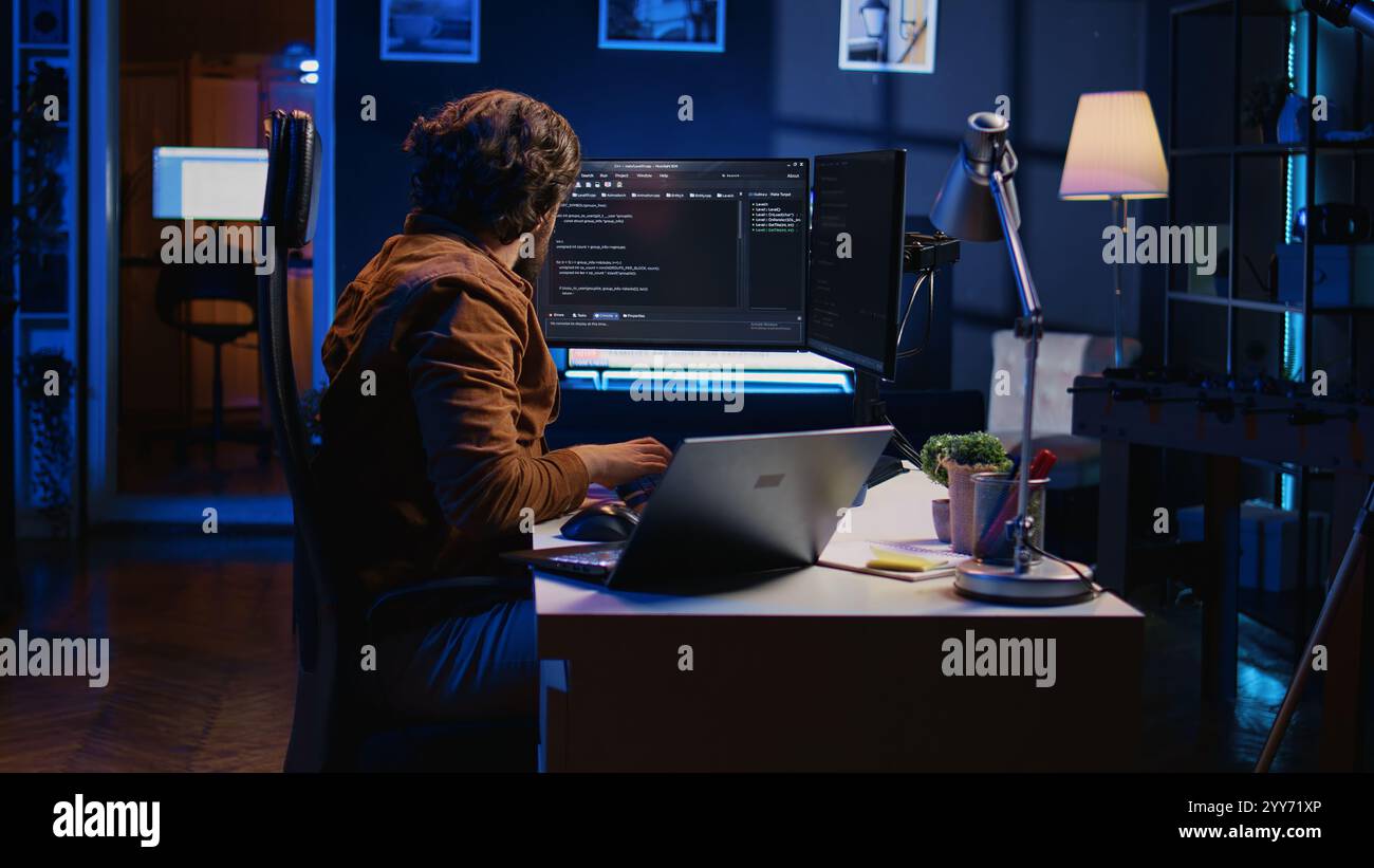 Software programmer putting headphones on while developing code, making time pass faster during remote job shift. IT professional doing multitasking in apartment office while listening music, camera B Stock Photo
