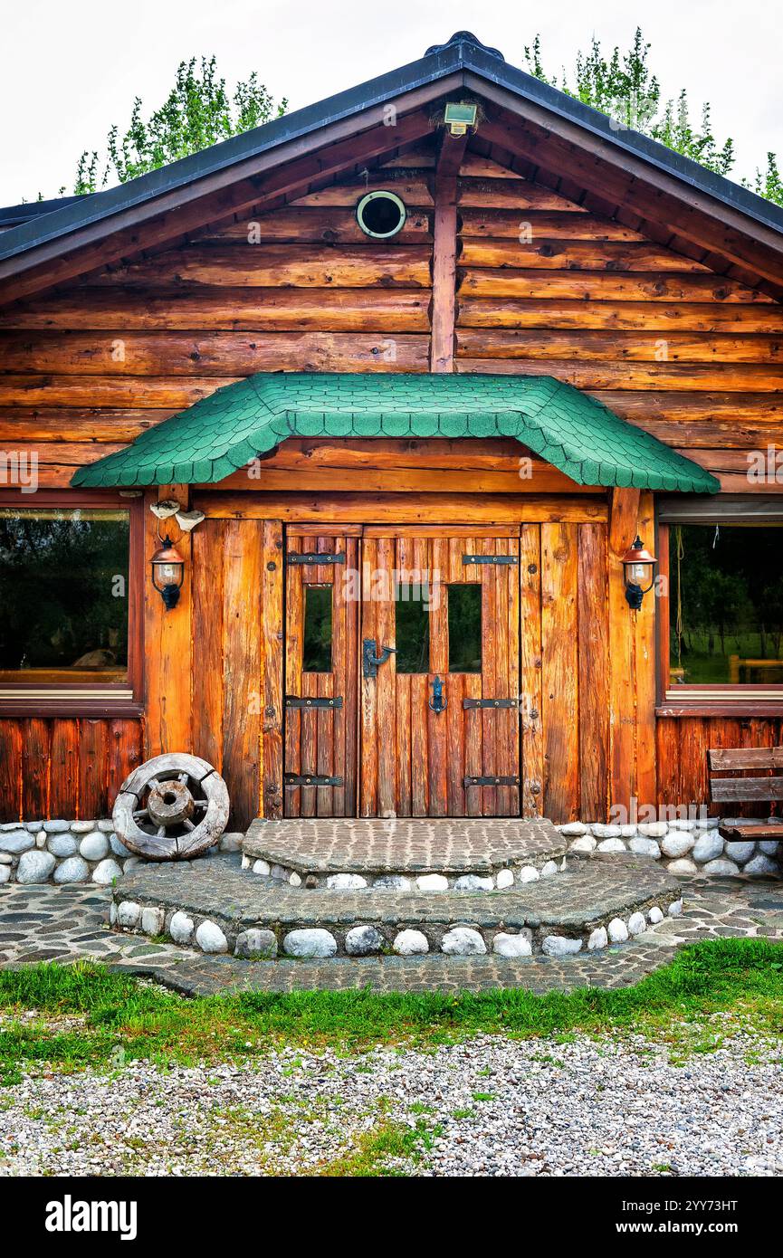 Wooden brown cottage in the countryside with a wheel on the porch Stock ...