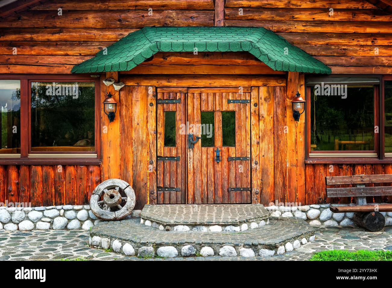 Wooden brown cottage in the countryside with a wheel on the porch Stock ...