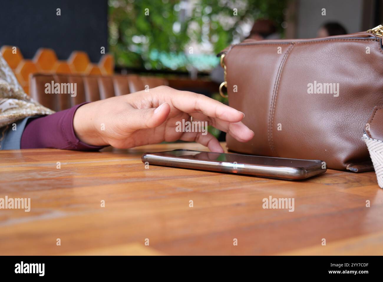A hand grabbing and picking up mobile phone on the table. Stock Photo