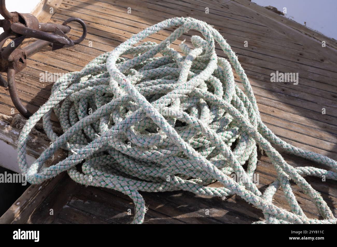 Nautical scene featuring a coiled rope on a weathered wooden deck ...