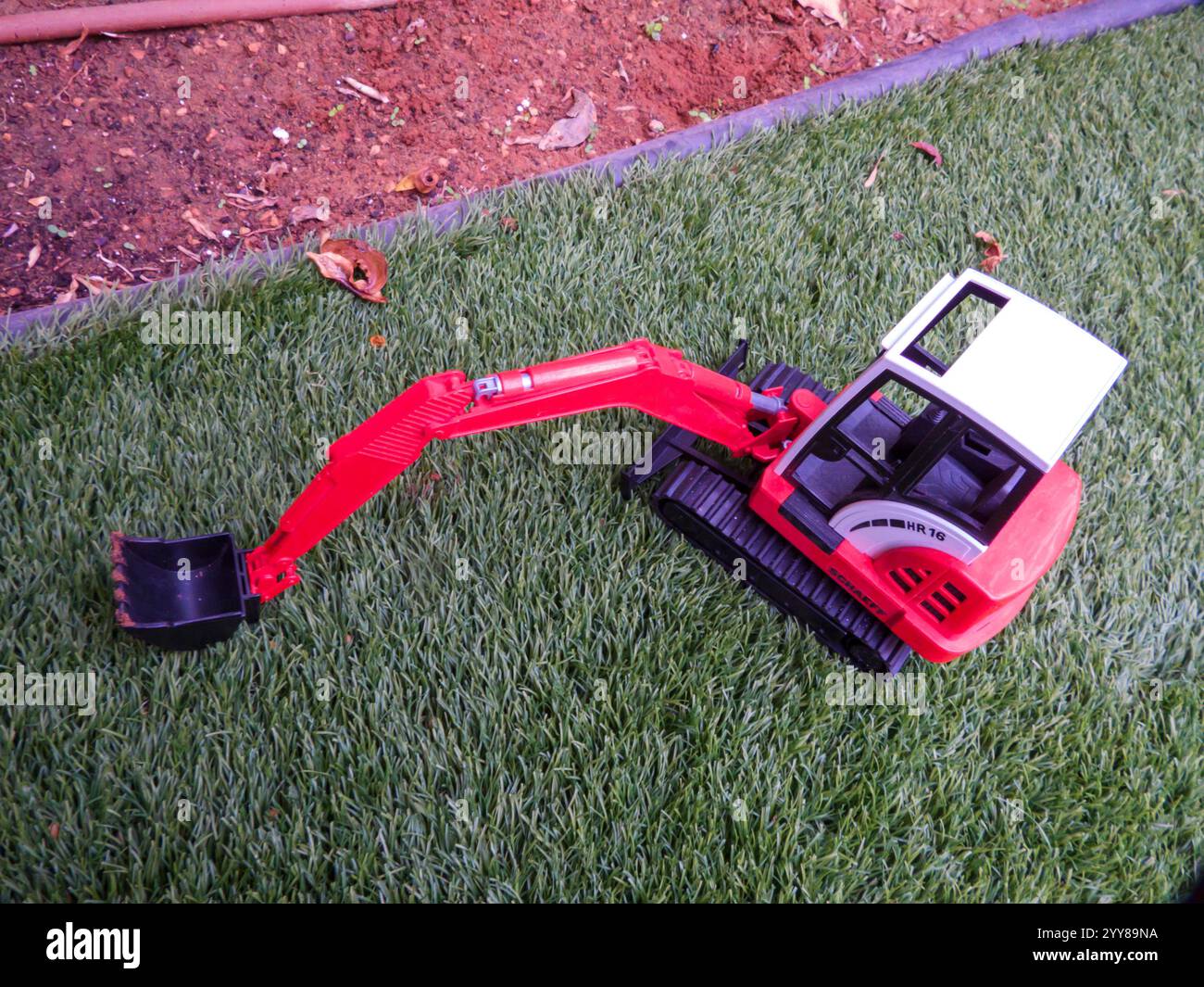 Toy Backhoe loader on the grass in the back yard Stock Photo