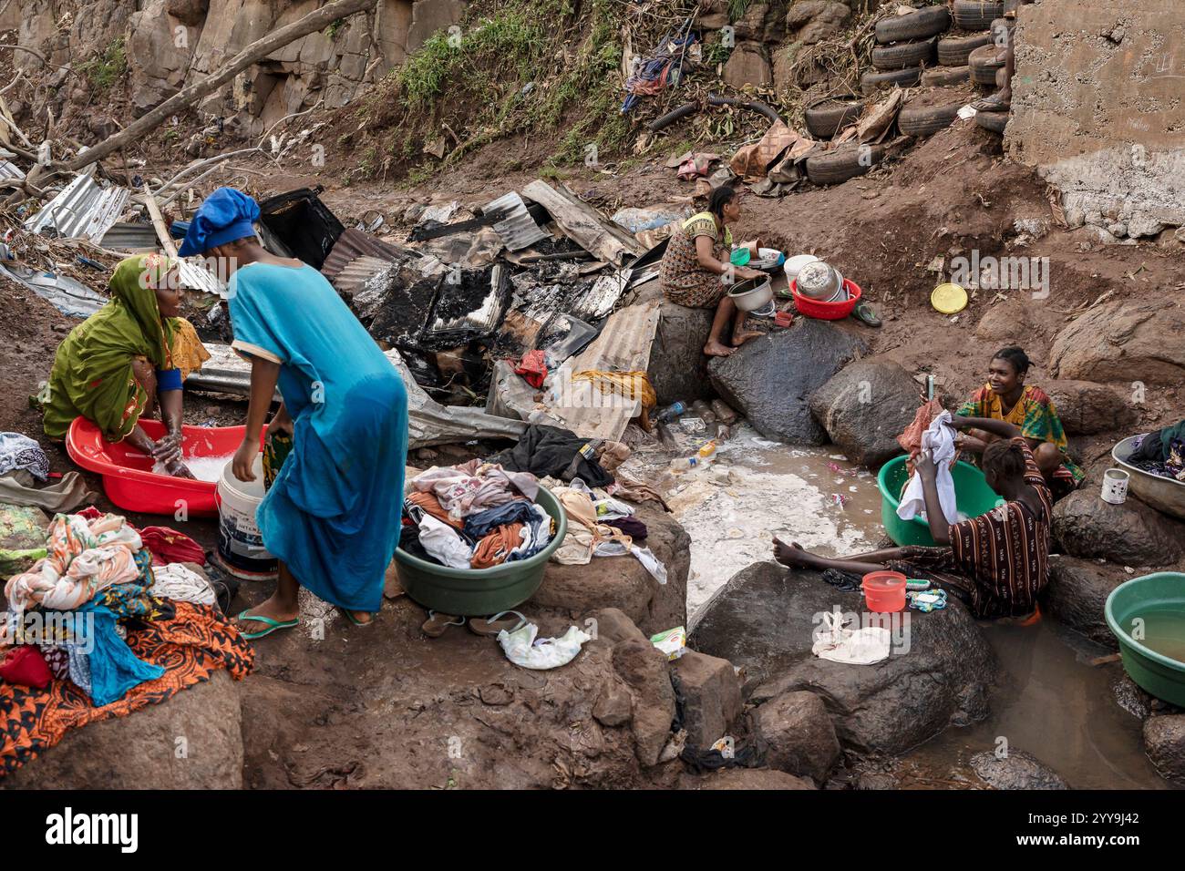 Women wash clothes in a stream in the Kaweni slum on the outskirts of