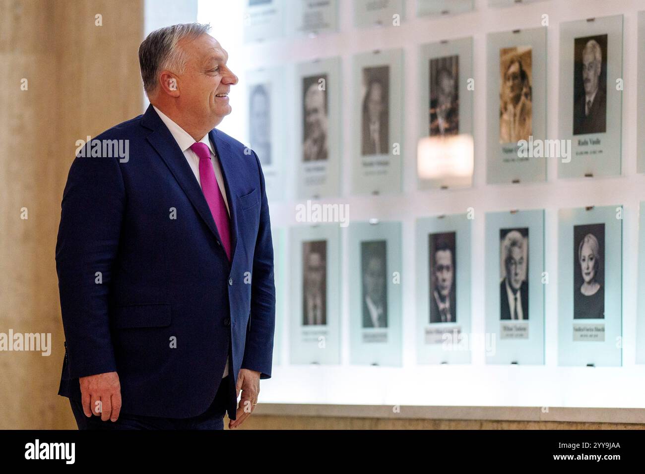 Hungarian Prime Minister Viktor Orban smiles while looking at portraits