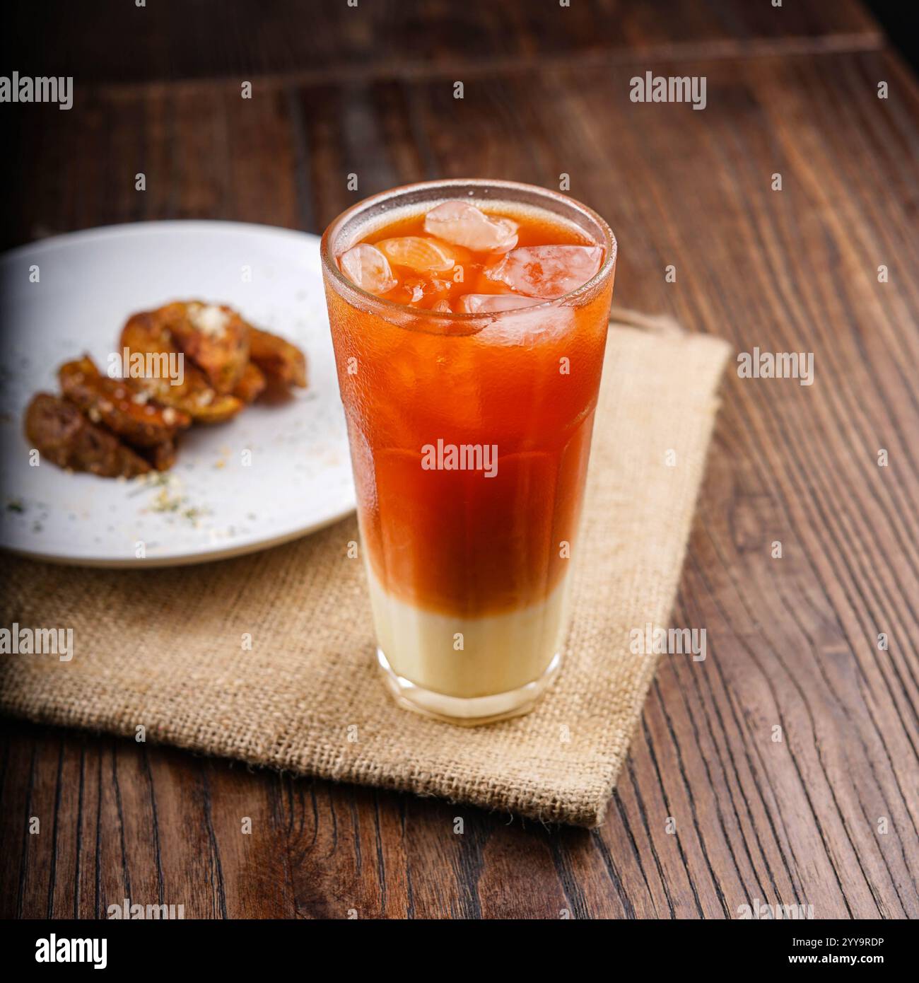 A refreshing glass of traditional Thai iced tea with sweetened condensed milk, served over ice in a tall glass, showcasing its iconic orange and cream Stock Photo