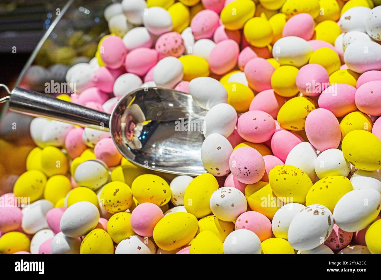 background of multi-colored chocolate eggs covered with icing with a spoon for soaking. Easter, Easter eggs Stock Photo